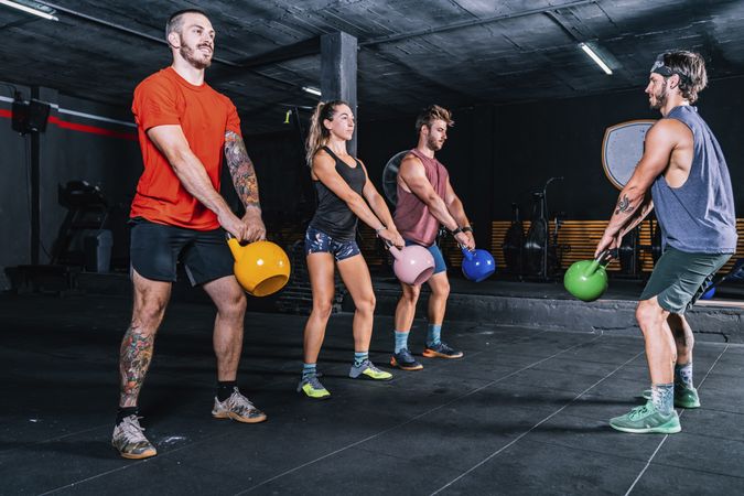 Athletic friends exercising with weight in gym