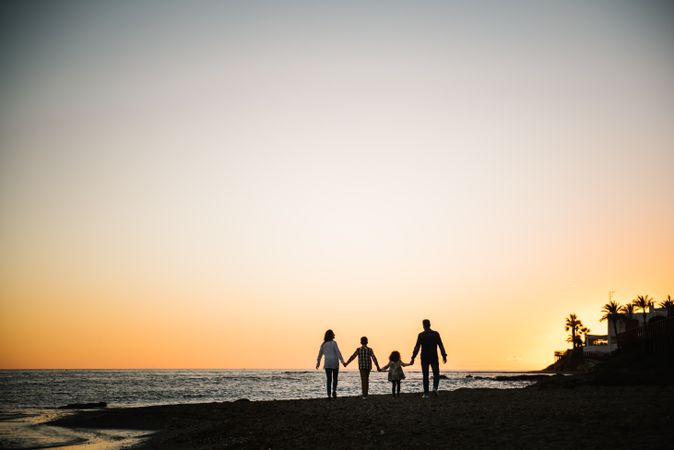 Silhouette of family holding hands at sunset