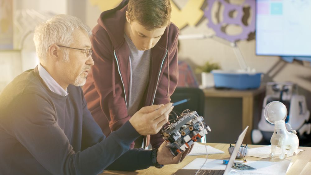 In Computer Science Class Teacher Examines programed Robot Engineered by His Student for School Project.
