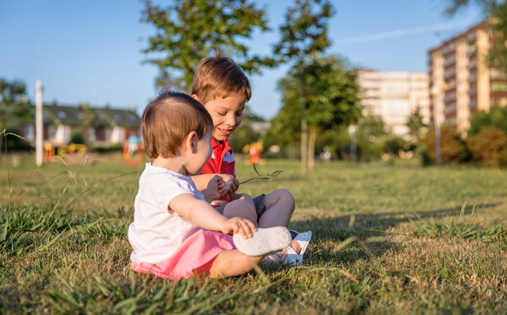 Baby girl and child playing sitting on a grass park