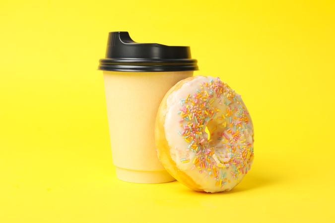 Paper cup and donut on yellow background