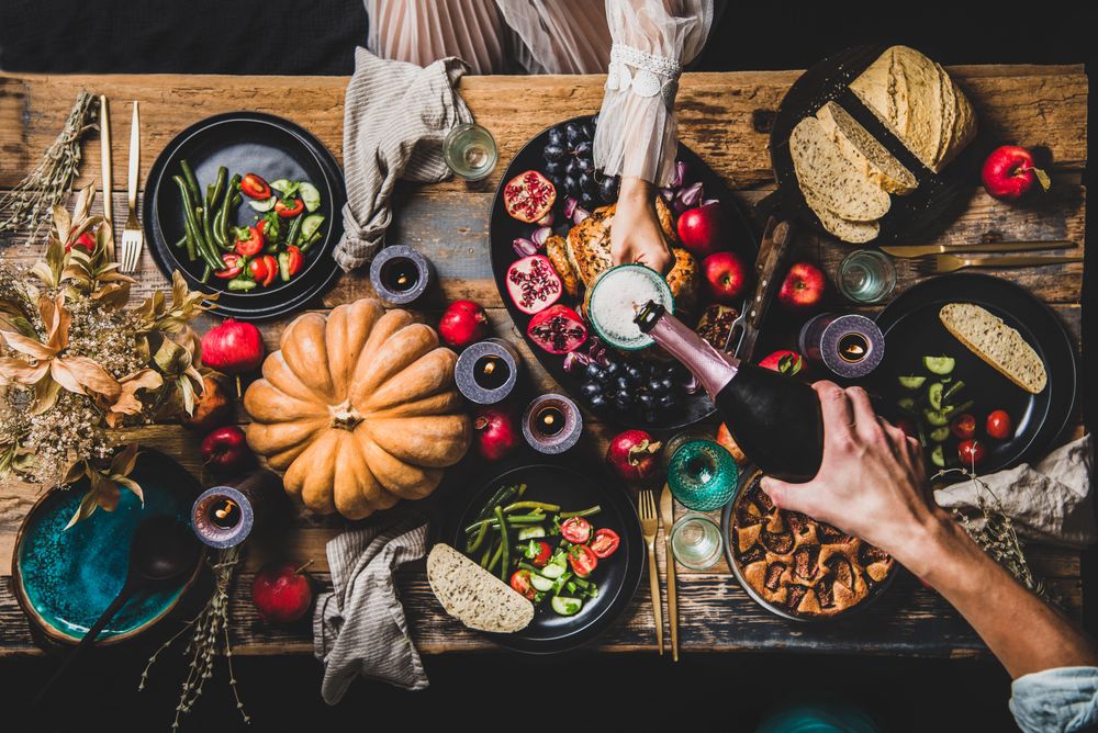Autumnal table with squash and candles with man pouring a glass of champagne for a woman in lace