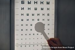 Cropped image of a person holding a pointer towards Snellen eye chart 4mKVd0