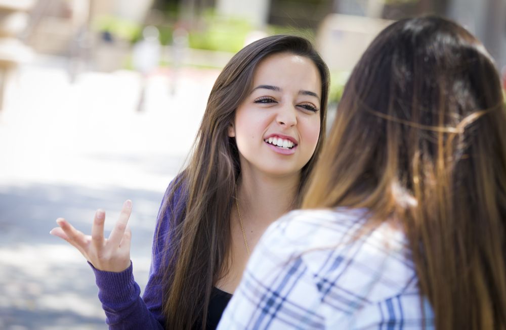 Expressive Young  Woman Sitting and Talking with Female Friend