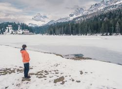 Unrecognizable person standing in snow surrounded by forest and mountains