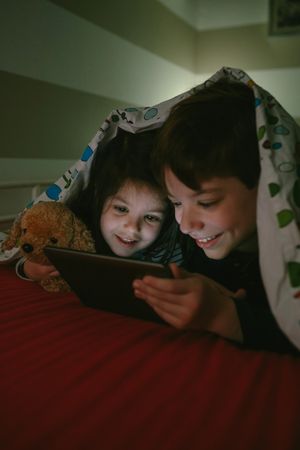 Siblings looking at the tablet in the dark