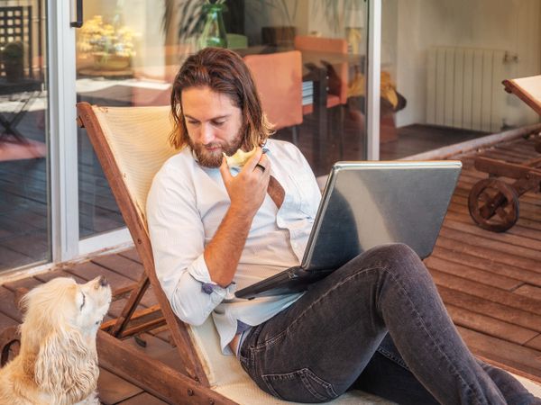 Man with laptop giving apple core to dog
