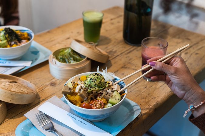Crop woman eating poke dish in restaurant