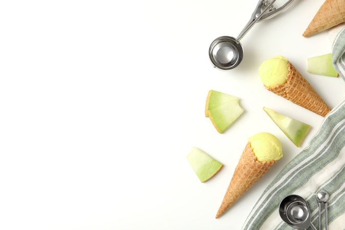 Ice cream cones with pieces of fresh melon on a plain background