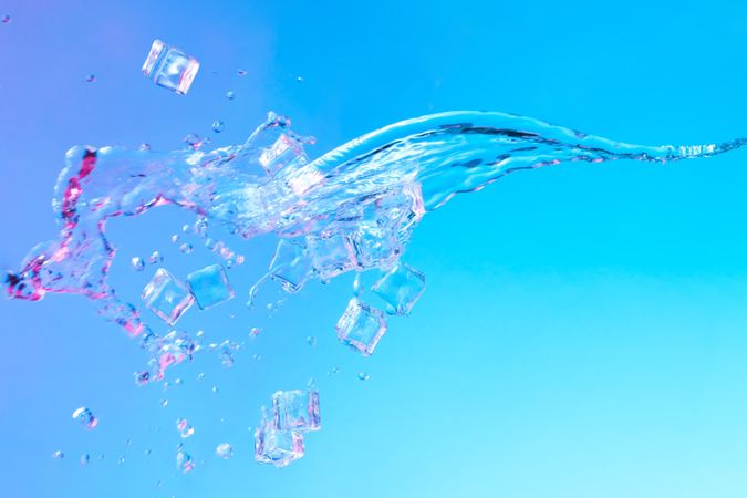 Ice cubes and splash of water in vibrant bold gradient purple and blue holographic color lights