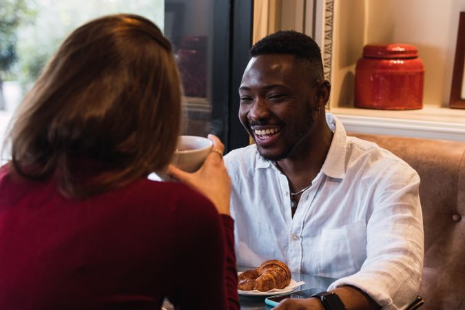 Multiracial couple having breakfast in cozy cafe