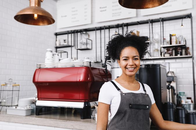 Smiling barista standing proudly in front of machines