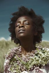 Black woman wearing floral wreath around her neck closing her eyes 41vlZb