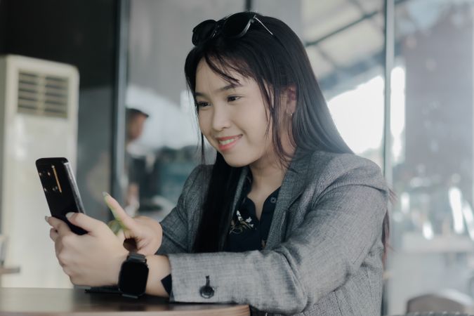 Young businesswoman using smartphone for video call at a cafe ta