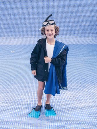 Cheerful boy in mask and flippers in empty pool