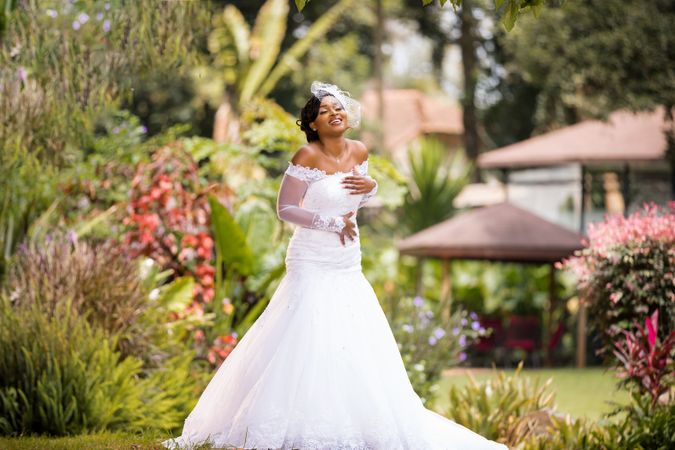 Smiling Black woman posing in wedding dress in the park
