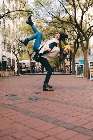 Young woman lifting up her friend acrobatically in street