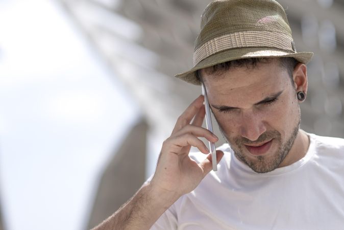 Male in hat speaking on phone outside