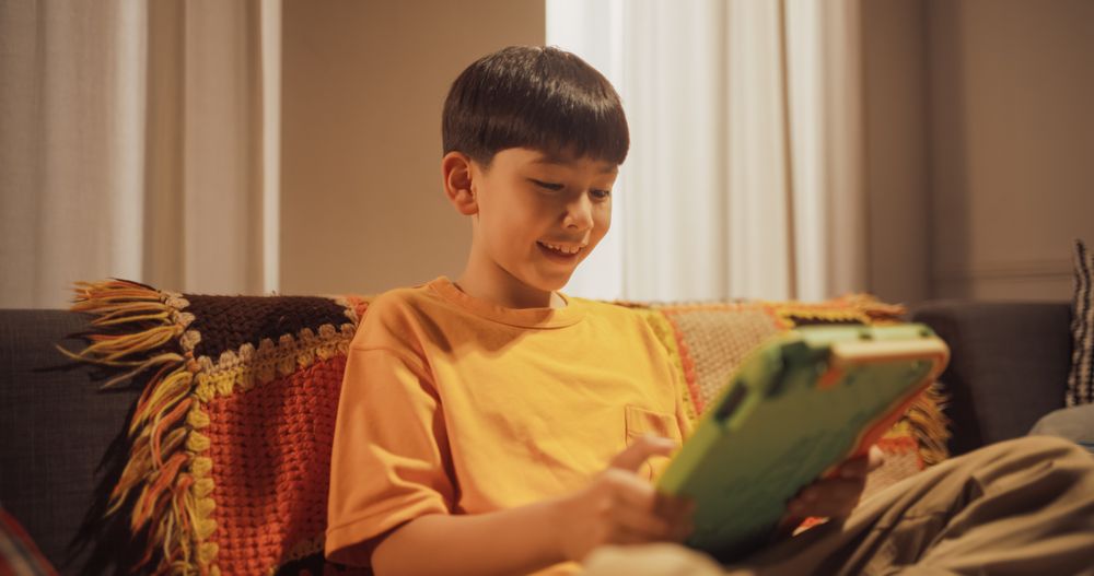 Portrait of Smart Little Boy Using Digital Tablet Computer in the Living Room at Home.
