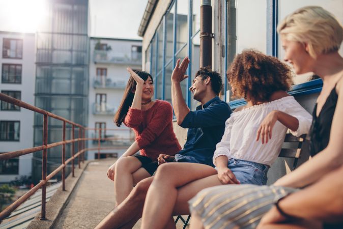 Multiracial group of friends having fun in balcony and giving high fives