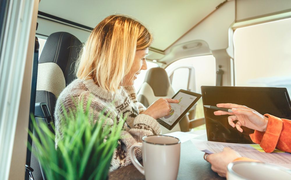 Friends working remotely in back of van while camping