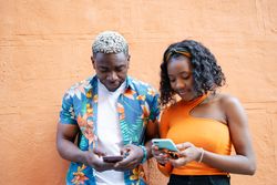 Young Black friends using smartphone in the street