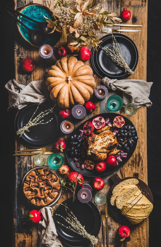 Thanksgiving table setting for gathering, with roast chicken, squash, pie, vertical composition
