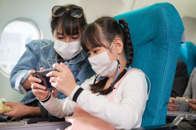 Mother and daughter checking phone together in airplane