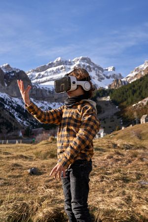 Preteen boy in virtual reality goggles simulating motion in moun