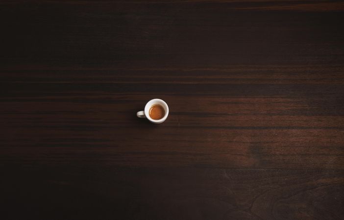 Single espresso shot pictured on wooden table