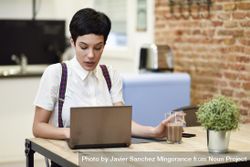 Woman in loft apartment concentrating on work on her laptop bepPG4