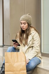 Cute woman sitting outdoors while using a phone