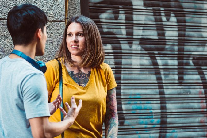 Joyful multiracial friends talking while standing on city street