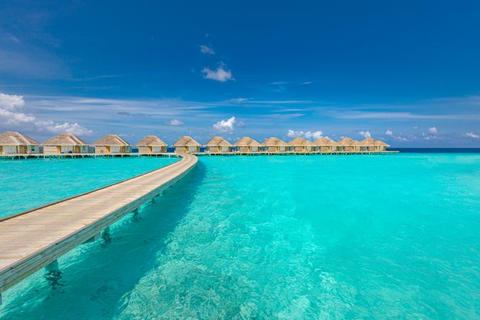 Walkway on crystal clear tropical water with overwater bungalows