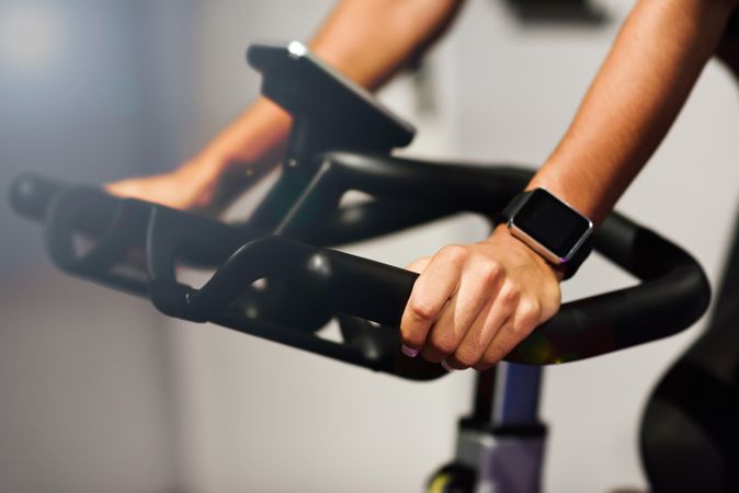 Hands of a female training at a gym doing indoor biking with smart watch