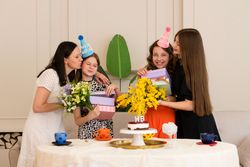 Family gathered around birthday cake with colorful hats
