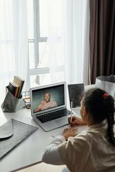 Girl using laptop and writing a note on a paper