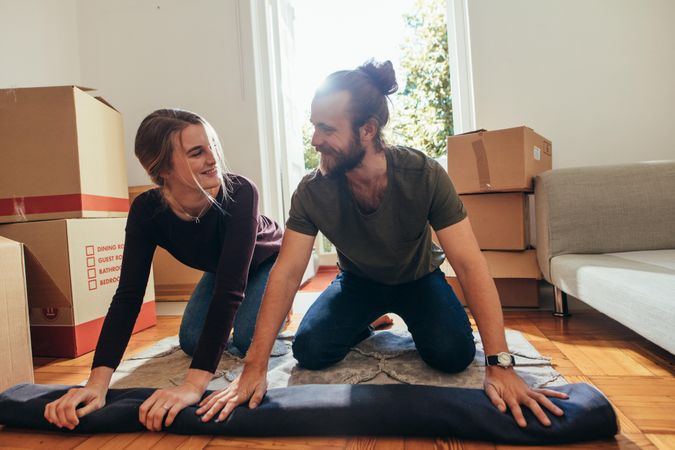 Young couple packing up their area rug