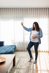 Happy pregnant woman taking selfie on smartphone
