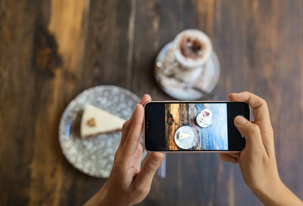 Faceless person taking picture of cake and coffee