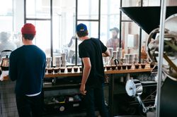 Back view of two men in coffee roasting facility preparing for a coffee tasting
