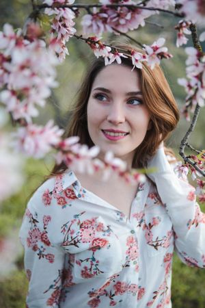 Young happy woman between trees in garden