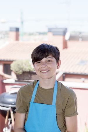 Portrait of smiling teenager standing on terrace wearing a gardener apron