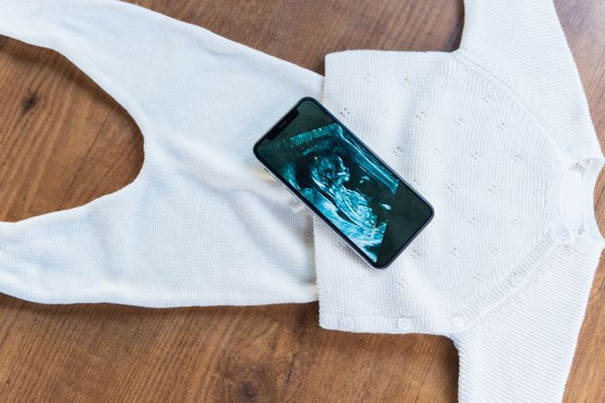 Smartphone with ultrasound baby picture on child outfit