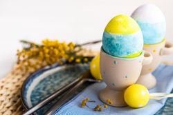 Top view of Easter table setting with with bird ornament and decorative eggs in cups