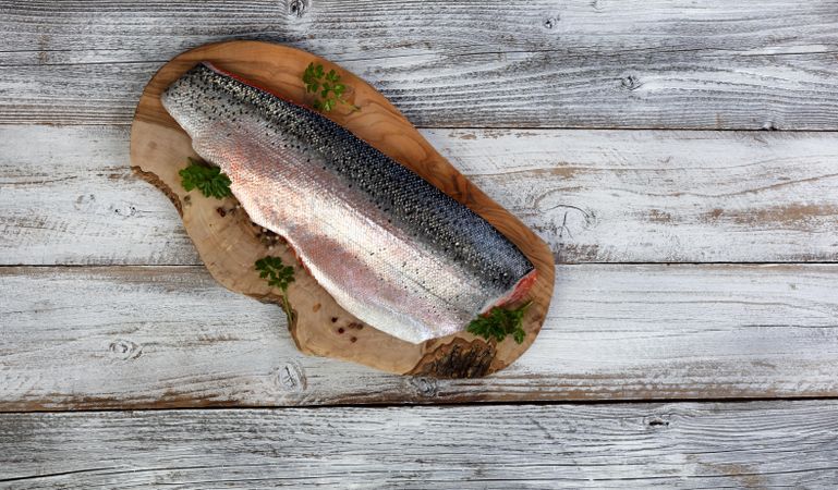 Rainbow trout fillet on olive board with skin upside