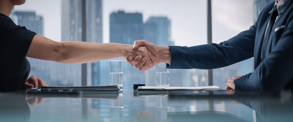 Close Up Of Female and Male Business Partners Sign Successful Deal and Shake Hands in Skyscraper Office.