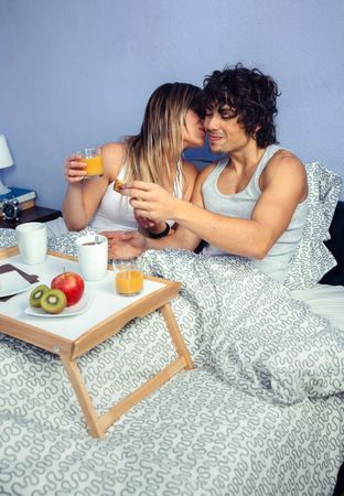 Woman kissing man in bed over breakfast