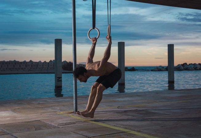 Athletic man balancing on gymnastic rings