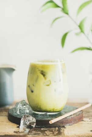 Iced matcha drink with pitcher on side, with eco friendly straw and leaves